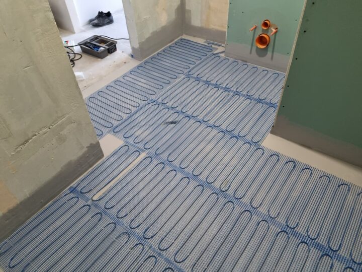 Maty grzewcze rozłożone wokół stelaża WC w remontowanej łazience